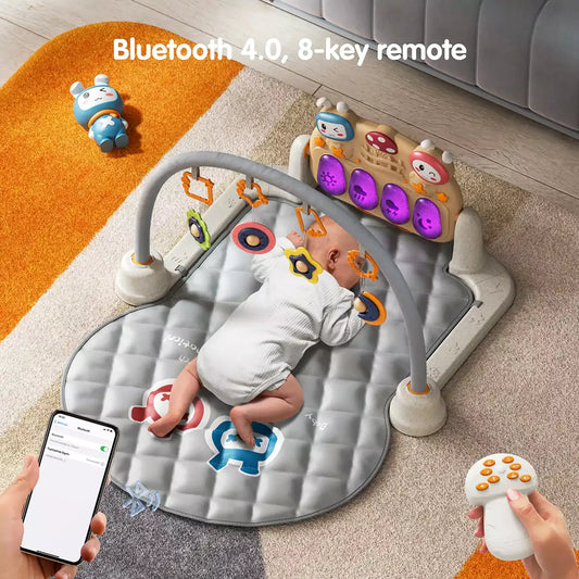 Baby tummy time on gray baby gym mat with hanging rattles, interactive musical piano keyboard with colorful lights, Bluetooth 4.0 and 8-key remote control.