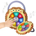 Hedgehog-shaped baby musical drum toy with a carry handle, featuring colorful light-up buttons in rainbow colors. A child’s hand is shown pressing one of the glowing keys, while musical notes float around, highlighting the toy’s interactive sound and light features.