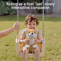 Smiling toddler sitting on a playground swing, holding a Shiba Inu interactive plush toy with tan and white fur. An adult hand gently steadies the swing. Overlay text reads: 'Acting as a first 
