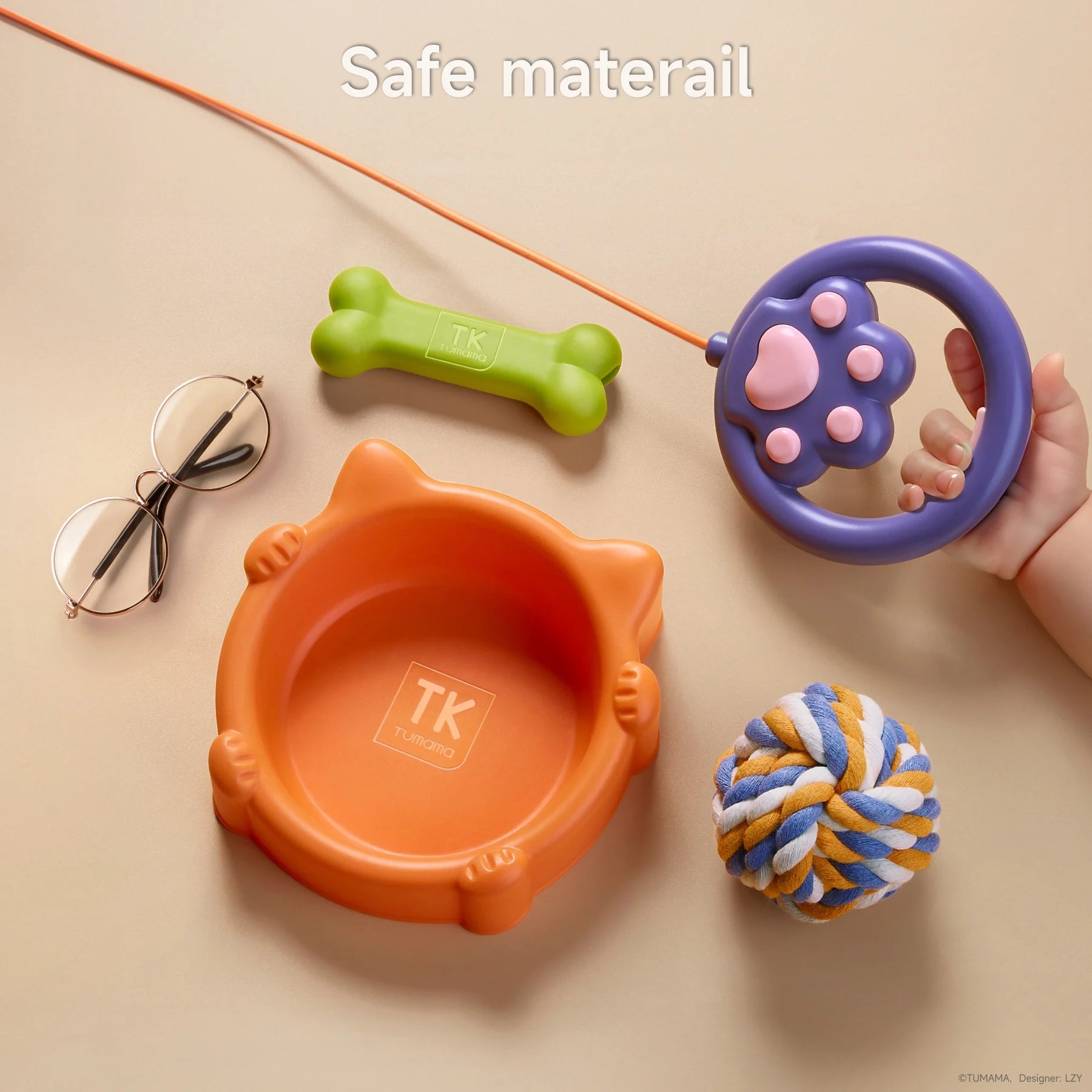 Walking doy toy set toy accessories laid out on a beige surface, including an orange pet bowl with 'TK Tumama' branding, a green bone, a blue and orange rope ball, a purple paw-shaped controller held by a child’s hand, and a pair of glasses.