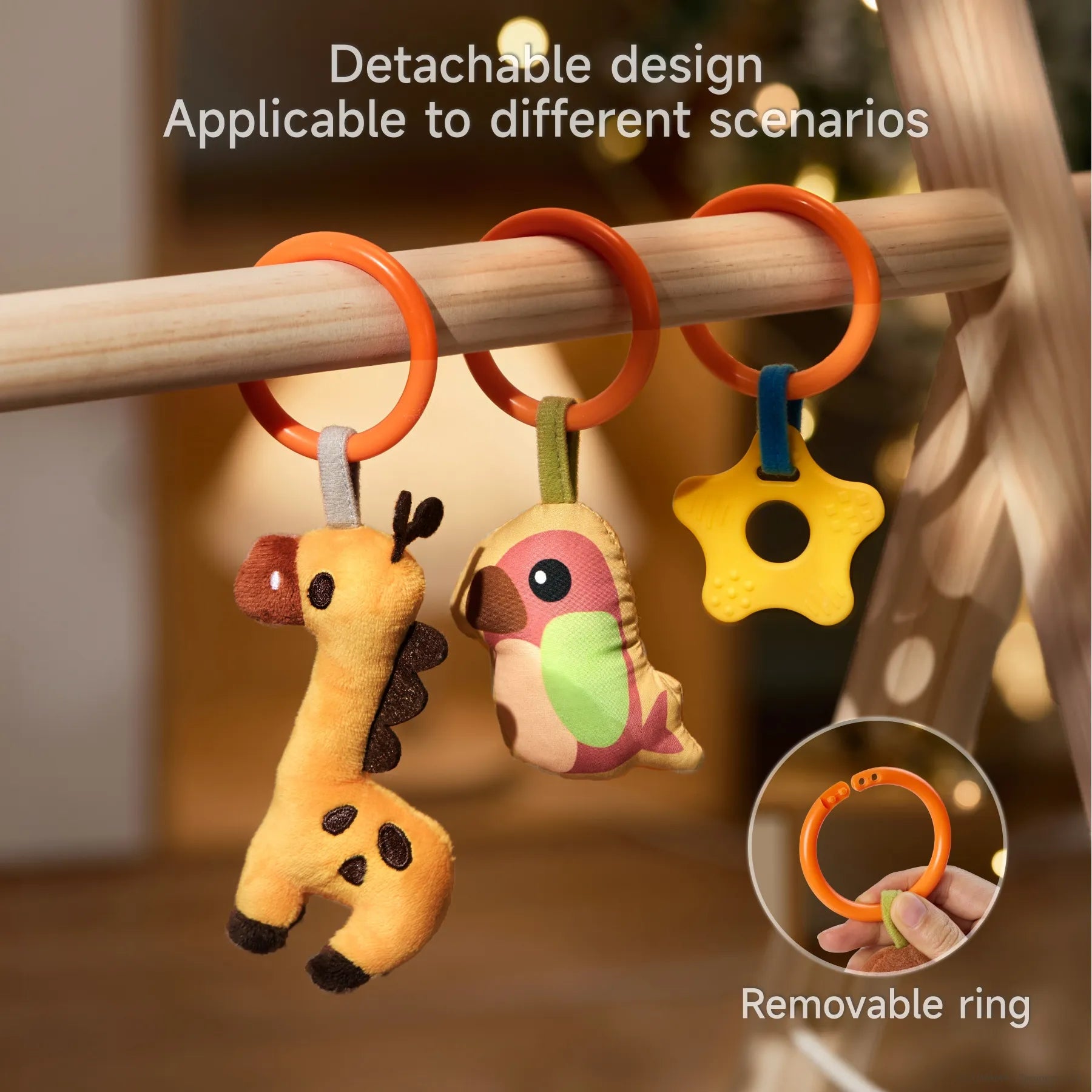 Close-up view of detachable plush baby toys—giraffe, bird, and star-shaped teether—hanging on orange removable rings from a wooden play gym, with an inset showing the ring's openable design for versatile attachment.