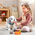 Little girl engaging in pretend play by feeding a realistic plush toy dog with a bottle; the dog wears a blue collar labeled “Tony” and is surrounded by toy accessories including a ball, bone, and food bowl in a cozy indoor setting.