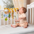 Baby sitting in a white crib, reaching toward a colorful plush spiral toy wrapped around the crib rail, featuring hanging soft figures of an elephant, tree, lion, and giraffe, designed to engage with bright colors and playful design.