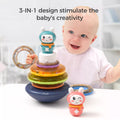 Smiling baby playing with a colorful stacking rings toy topped with a bunny figure. The toy features a wobbling base, translucent rainbow-colored rings, and interchangeable bunny toppers. One ring is held in the baby’s hand like a rattle, while another bunny topper sits on the table. Text on the image reads: “3-IN-1 design stimulate the baby’s creativity,” emphasizing multiple play modes.