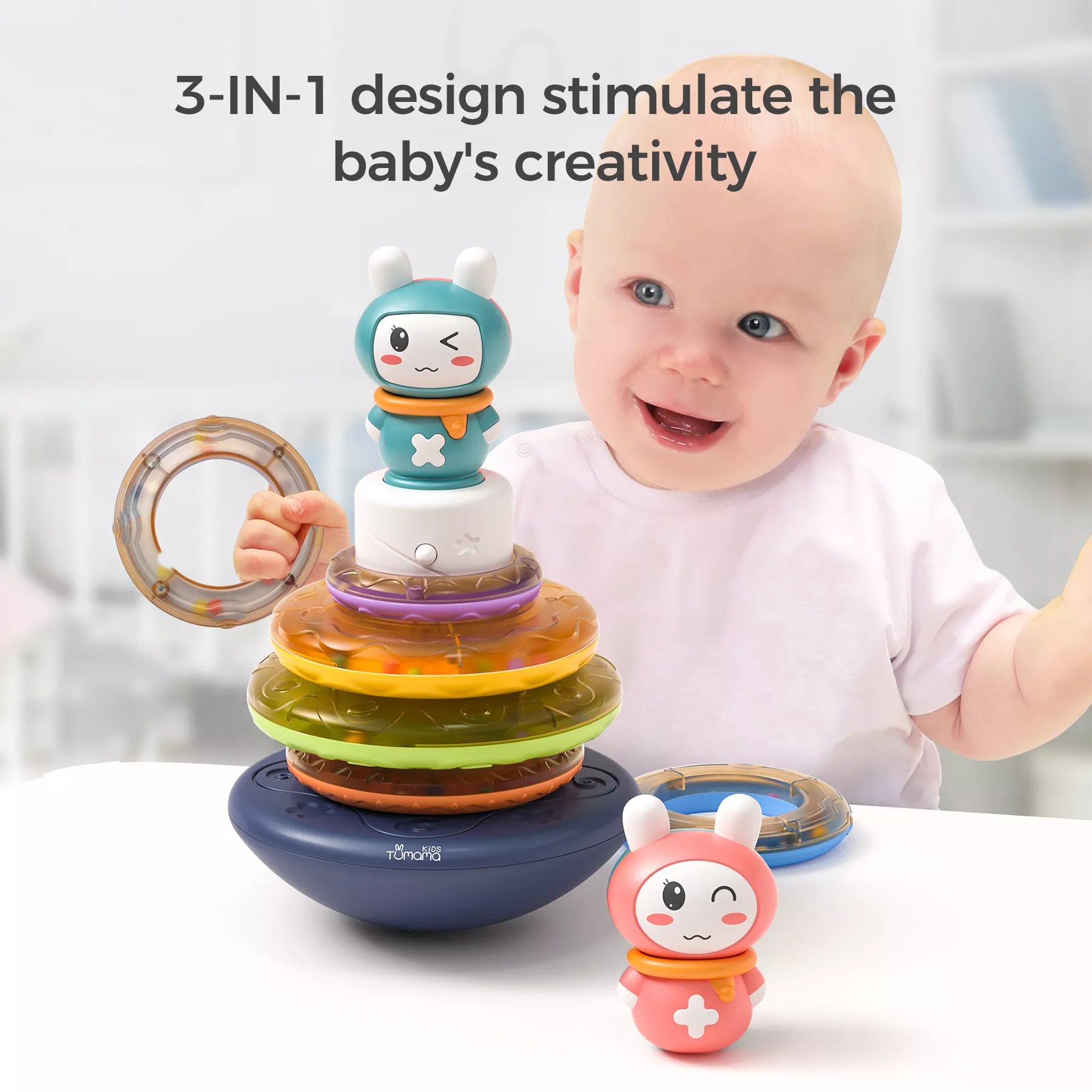 Smiling baby playing with a colorful stacking rings toy topped with a bunny figure. The toy features a wobbling base, translucent rainbow-colored rings, and interchangeable bunny toppers. One ring is held in the baby’s hand like a rattle, while another bunny topper sits on the table. Text on the image reads: “3-IN-1 design stimulate the baby’s creativity,” emphasizing multiple play modes.