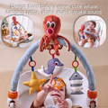 Baby reaching up to play with plush sea animal toys including a whale, star, and fish hanging from a soft arch toy bar designed from baby's view; two smaller insets show different babies engaging with the same toy.