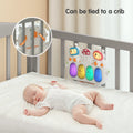 Baby sleeping peacefully in crib with light-up musical keyboard toy tied to crib bars, showing secure strap attachment.