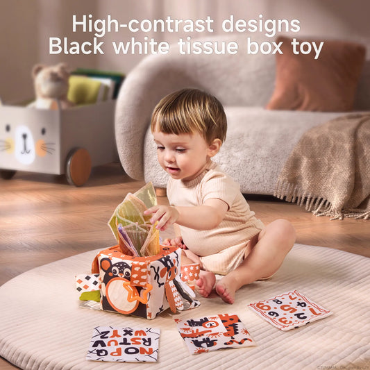 Baby playing with high-contrast black and white sensory tissue box toy and fabric cards for early learning and visual development in a cozy nursery