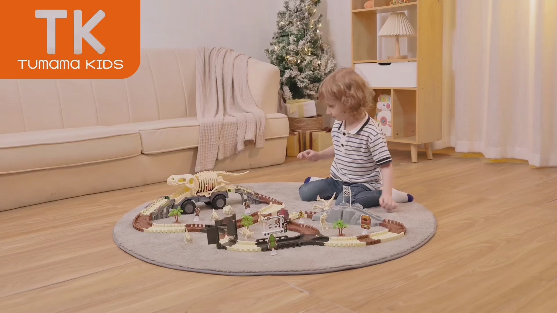 LITTLE BOY IS PLAYING WITH DINOSAUR RACE TRACK CAR TOY SET INDOORS