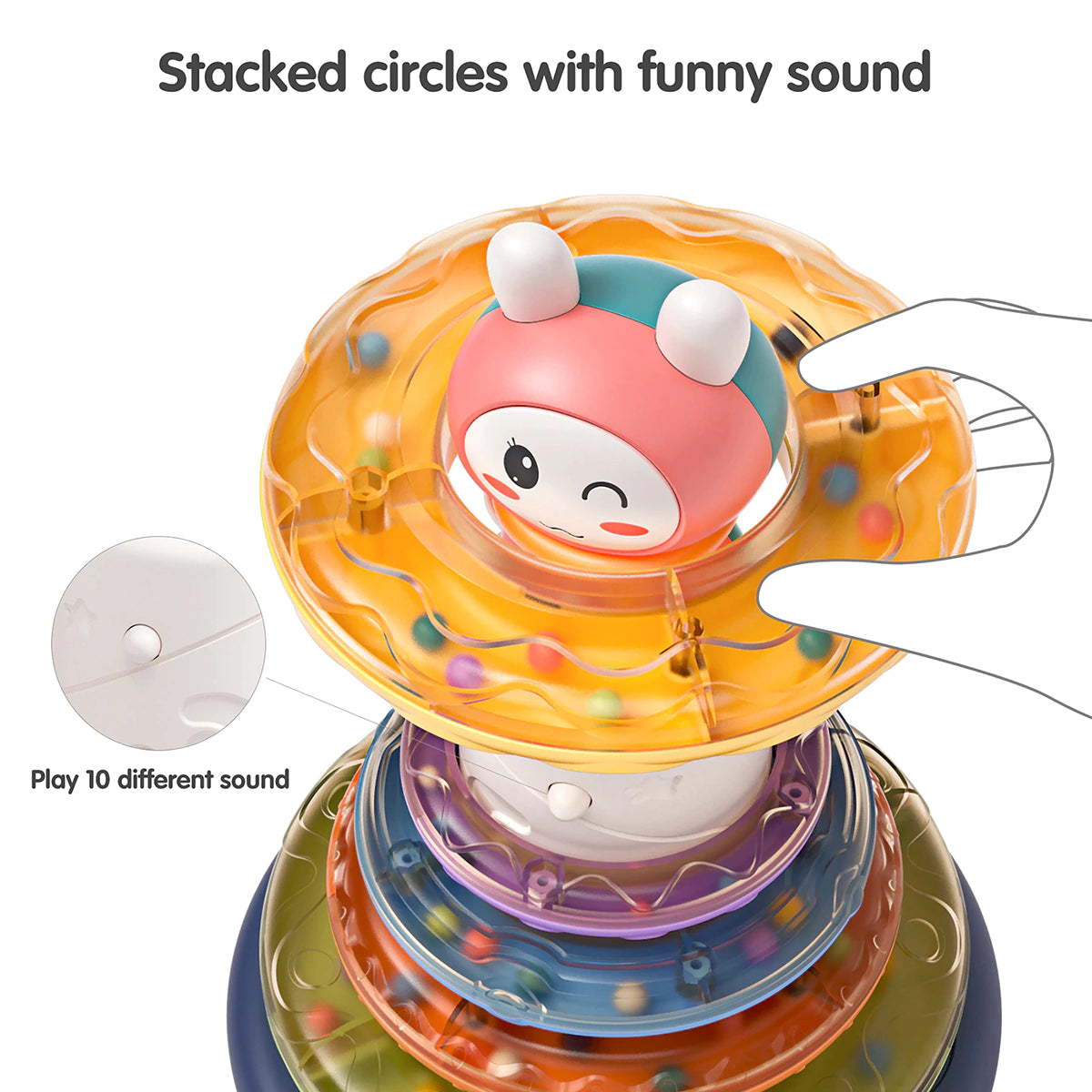 Close-up of a colorful stacking rings toy with a bunny topper. A hand is lifting one of the translucent orange rings filled with small beads, showing that each ring can also be used as a rattle. Text on the image reads: “Stacked with sound, but can be a rattle,” with an inset detail noting: “Play 10 different sound.”